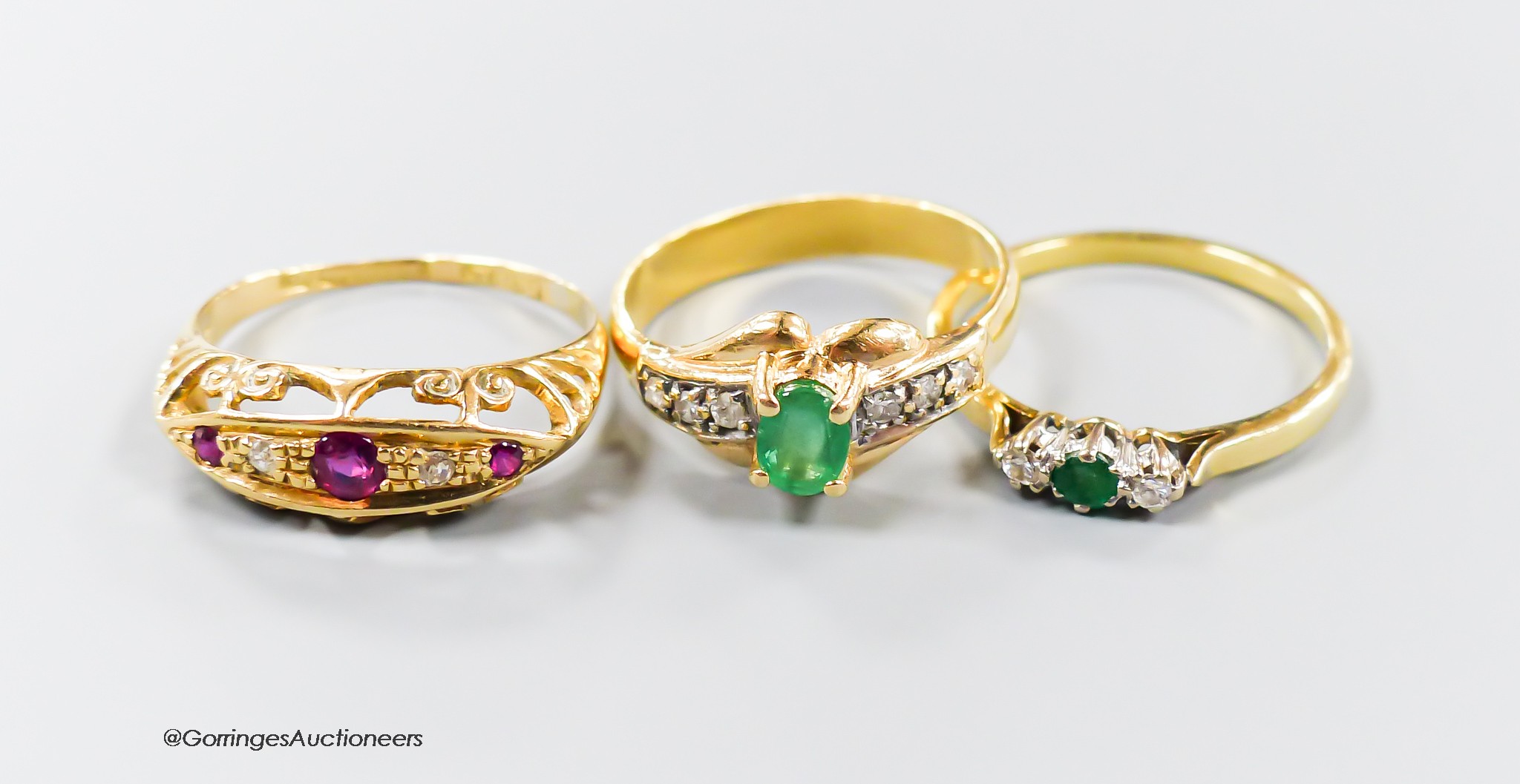 Three assorted modern 18ct gold and gem set rings, including emerald and diamond, ruby and diamond, gross 6.9 grams.